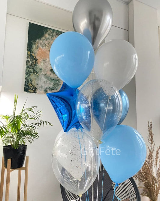 Decorative arrangement of blue, silver, and clear balloons in a room with plants and artwork.
