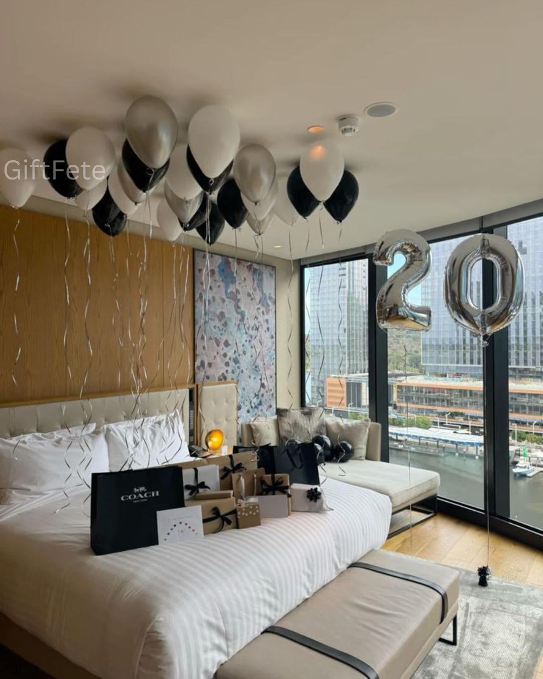 Decorated bedroom with balloons and '20' sign, featuring a Coach gift box.
