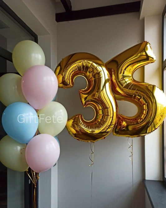 Gold number 35 balloon with colorful balloons against a neutral wall.