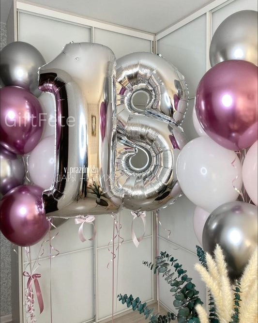 Silver number 18 balloons with pink and white balloons against a light-colored wall.