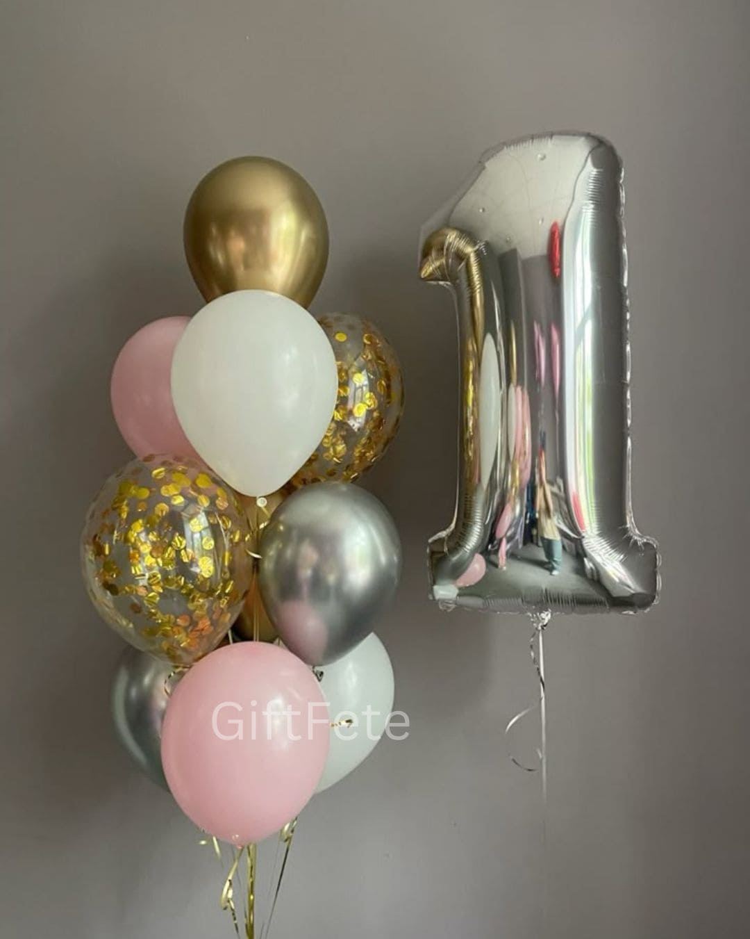 Decorative balloons with a number '1' foil balloon against a plain background